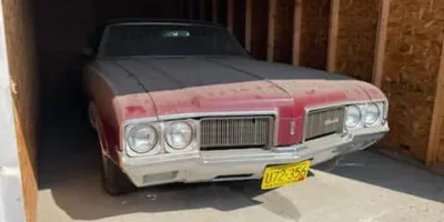 Dust-covered classic muscle car in storage before professional exterior detailing.