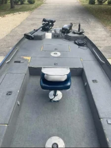 Empty bass boat cockpit with a single gray pedestal seat, viewed from the bow facing aft, with a casting deck and trolling motor visible.