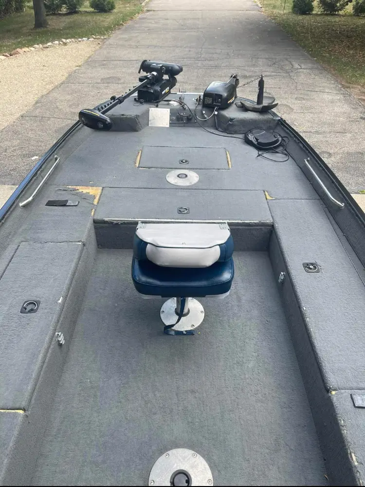 Empty bass boat cockpit with a single gray pedestal seat, viewed from the bow facing aft, with a casting deck and trolling motor visible.