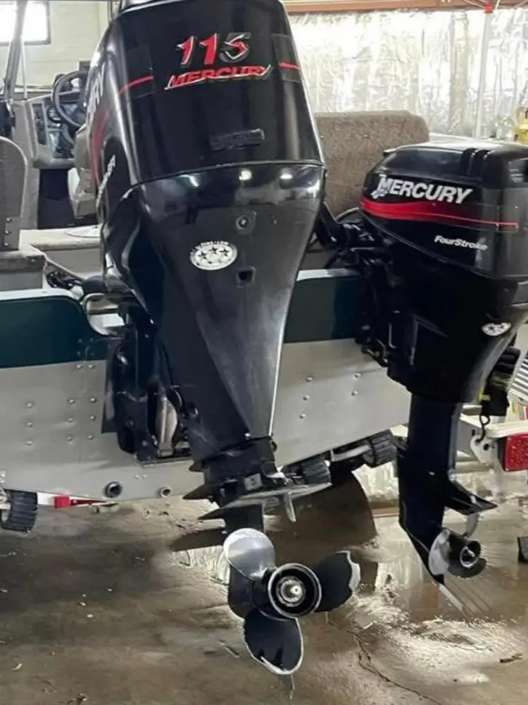 Close-up view of two Mercury outboard boat motors, one large and one smaller kicker, mounted on the transom of an aluminum boat.