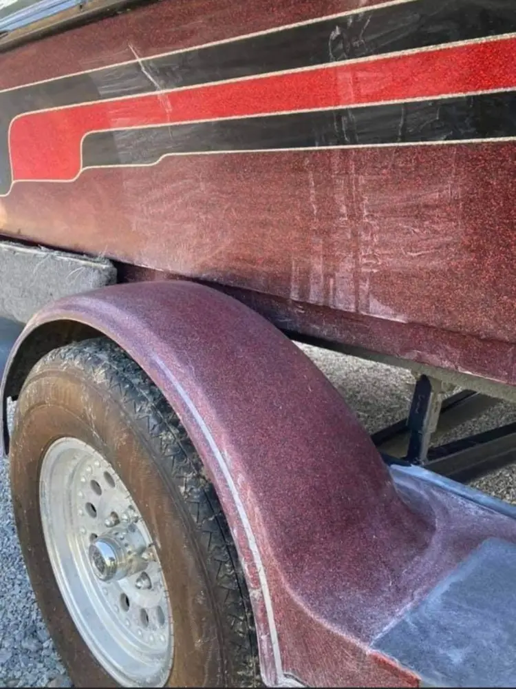 Close-up of a marron metallic bass boat trailer fender and wheel, showing textured flake paint finish.