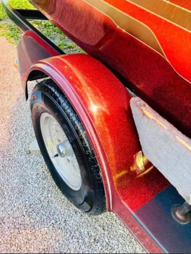 Close-up of a marron metallic bass boat trailer fender and wheel, showing textured flake paint finish.